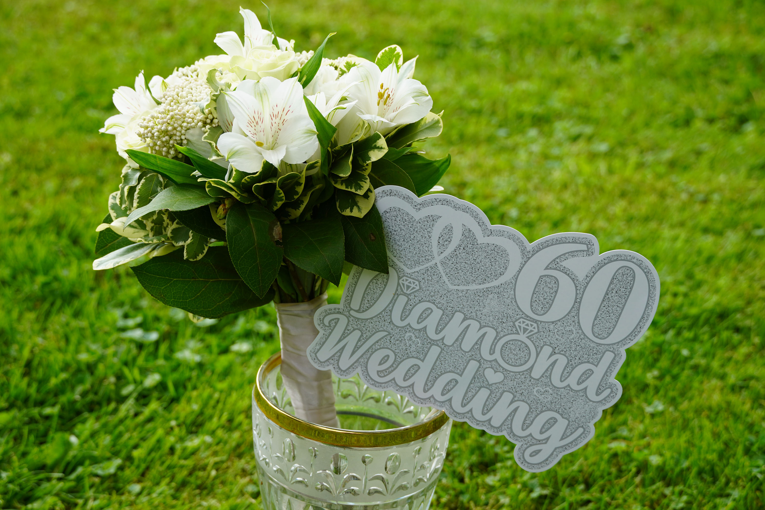 close up of a white flower bouquet with a sign that reads "60 diamond wedding"