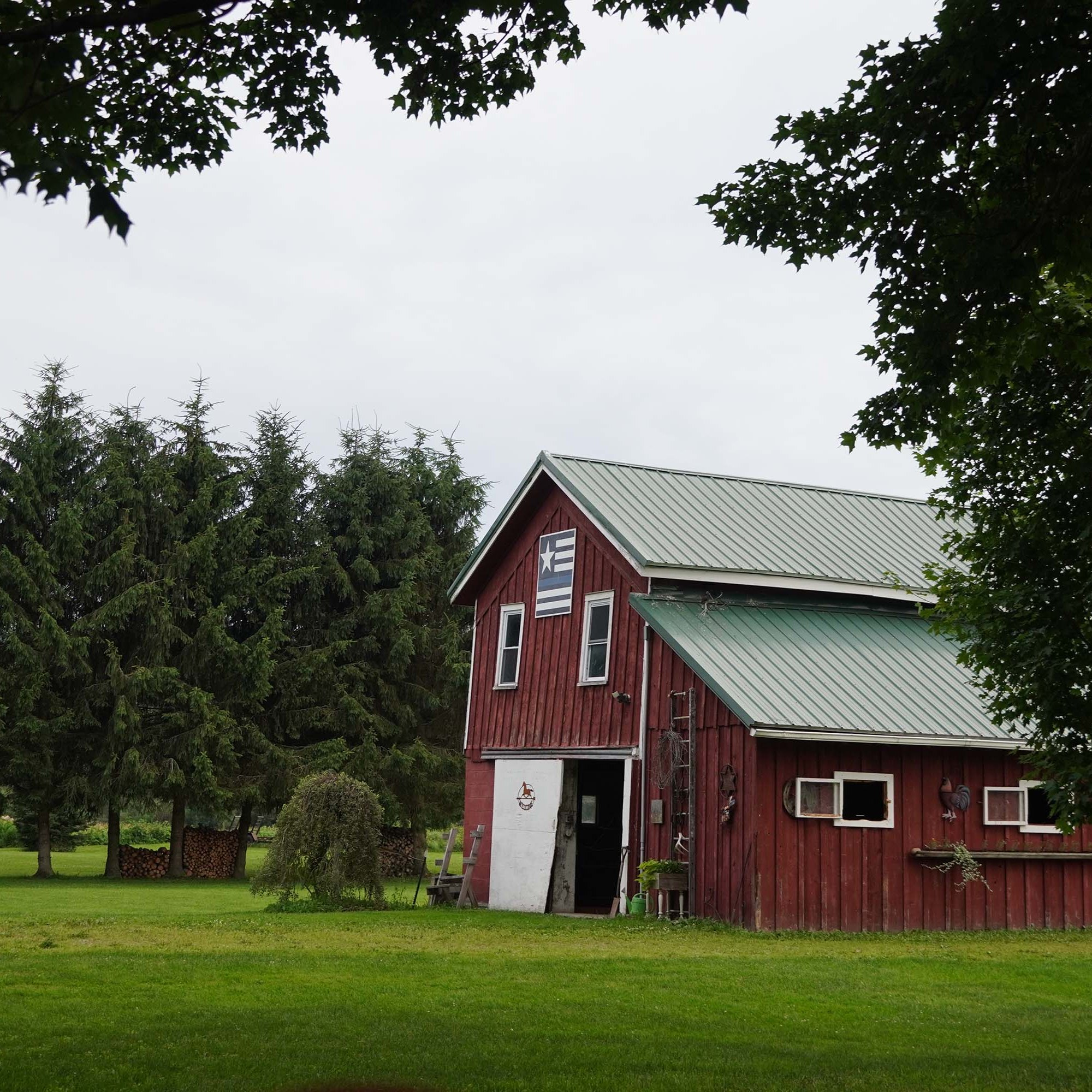 Red barn to the right with an open door and blue lines flag