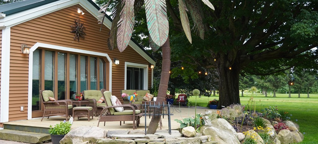 View of the back deck with a metal palm tree with wicker chairs with light green cushions