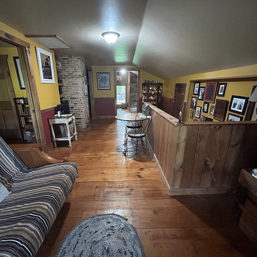 view of the sitting area towards the back with a couch on the left and the stairs going down on the right