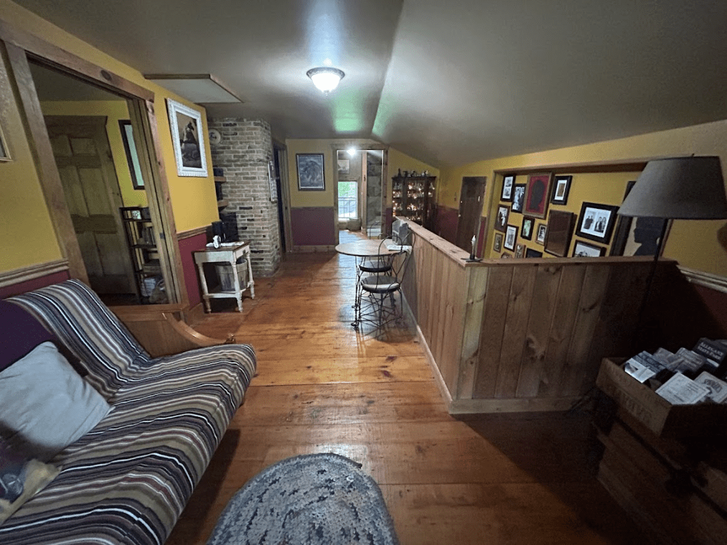 view of the sitting area towards the back with a couch on the left and the stairs going down on the right