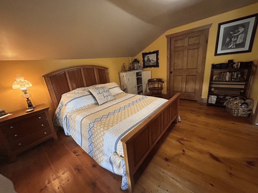 queen bed in a room with yellow walls taken towards the bedroom door